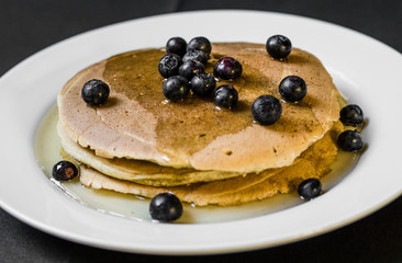 Close up of a tasty american pancake with blueberries and maple syrup. Selective focus.