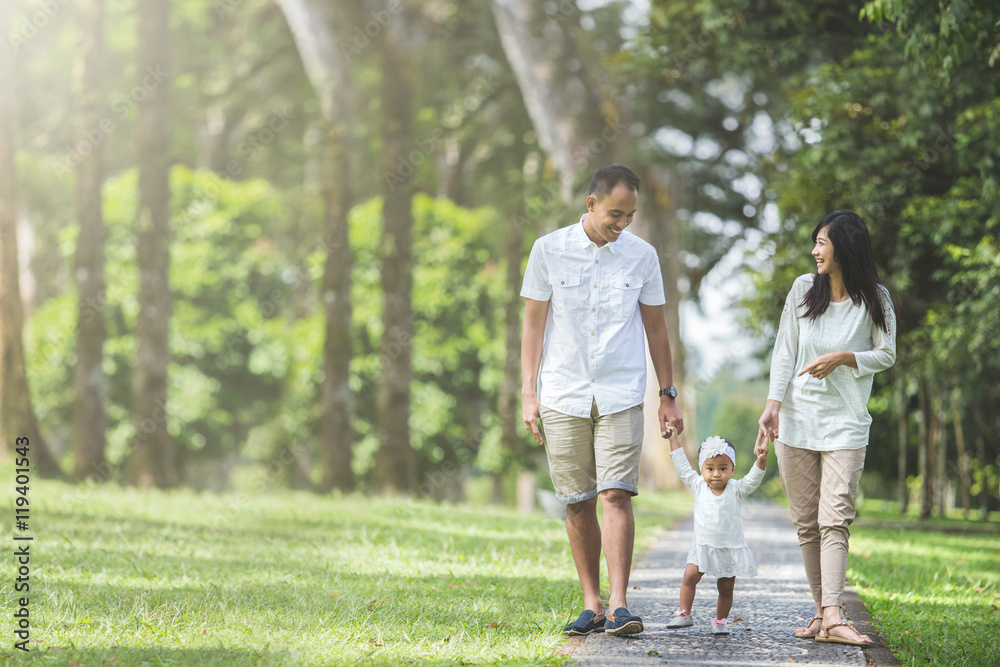 Wall mural family walking in the park together