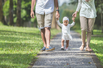 baby learn to walk for the first time with her parents hold her