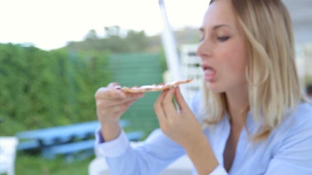 Pretty girl sitting in the restaurant and eating pizza.