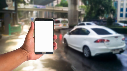 the hand of man hold mobile phone over blurred of traffic jam on the road