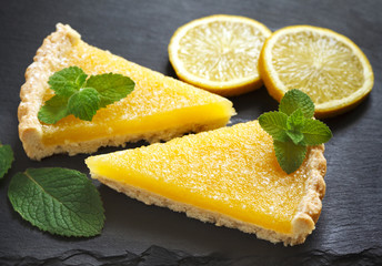 Two slices of lemon pie on black background