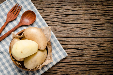 Organic fresh potatoes in wooden bowl with fabric background. Raw organic potato on old wooden background.