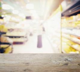 wooden table top with blur of supermarket with miscellaneous product on shelves