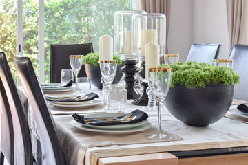 dining wooden table and comfortable chairs in modern home with elegant table setting