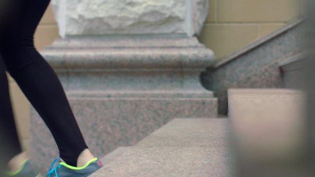 Woman legs in sport shoes walking down stairs. Legs in running shoes stepping down stairs. Closeup of woman legs in jogging shoes go down staircase. Girls legs jogging up staircase