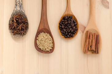 Cinnamon sticks, star anise, coriander seed and coffee grains on wooden spoon, seasoning ingredients for cooking or baking.