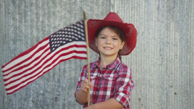 Young cowgirl waving american flag