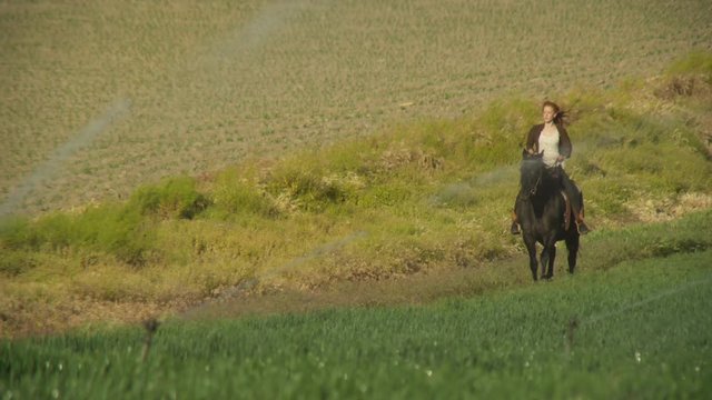 Blur in to young woman riding horse through green fields