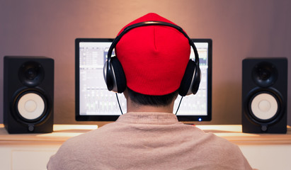 back of asian man listening music with professional audio equipment in home studio