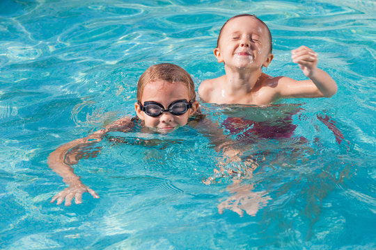 Two happy children playing on the swimming pool at the day time.