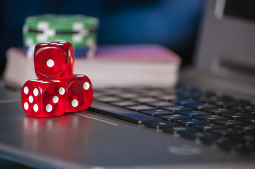 Gambling chips and red dice on laptop keyboard background