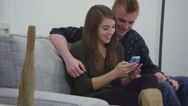 Young couple using cellphone in living room