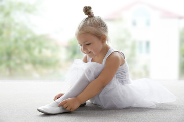 Cute ballerina sitting on the floor at ballet class