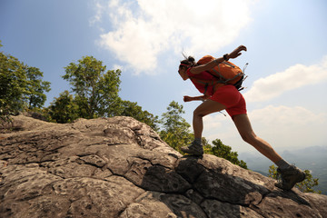 young asian woman hiker climbing rock on mountain peak cliff