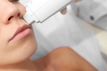 Woman getting laser treatment on her face in a beauty salon, close up
