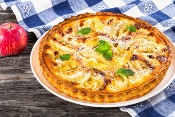 Apple pie sprinkled with icing sugar decorated with mint leaves