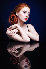Naklejka premium Young woman with ginger hair over reflection mirror on blue back