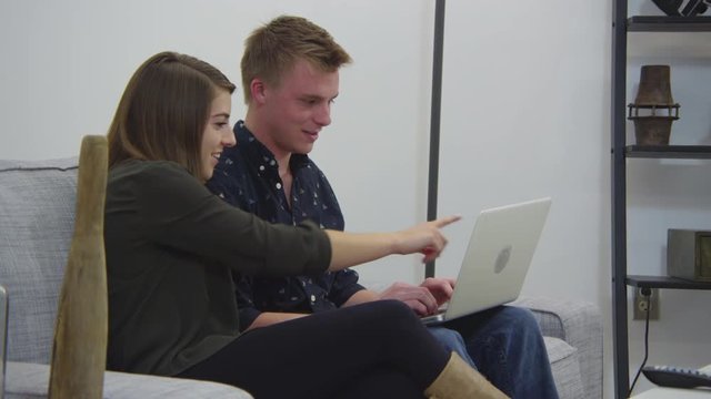 Young couple using laptop in living room