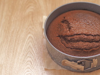 Freshly baked chocolate cake in baking pan upon wooden background. Selective focus. Copy space for your text.