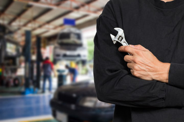 asian automotive mechanic holding wrench for maintaining car at repair shop