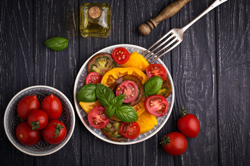 Colorful tomatoes salad in black background