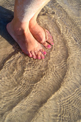 Woman's bare feet in water at the beach.