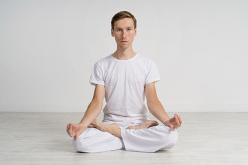 Young man meditating in Lotus position on the floor