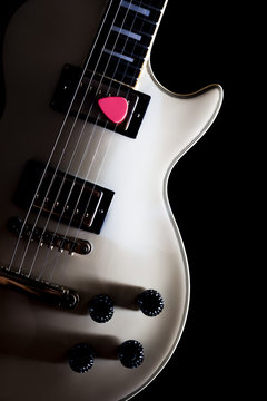 pink pick with white electric guitar, isolated on black + vintage filter for music background