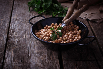Uncooked chick-peas on wooden bowl