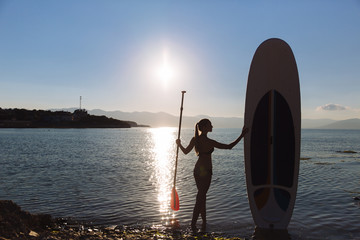 Silhouette of a beautiful woman on stand up paddle board. SUP, concept  lifestyle, sport