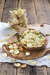 Uncooked colorful orecchiette in a wooden bowl. Italian pasta.