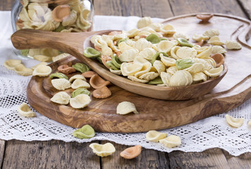 Uncooked colorful orecchiette in a wooden bowl. Italian pasta.