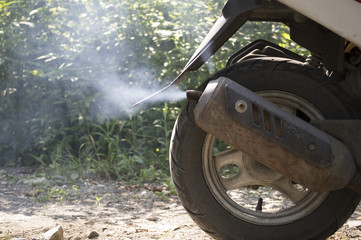 smoke from the exhaust pipe of a moped
