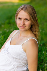 portrait of a pregnant woman sitting on the grass