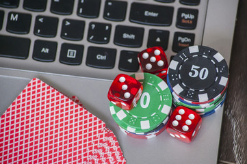 Gambling chips and red dice on laptop keyboard background