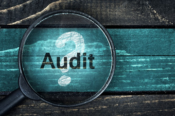 Audit text painted and magnifying glass on table