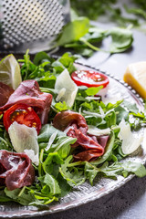 Dried beef bresaola. Salad bresaola arugula baby spinach tomatoes lime and cheese parmesan.