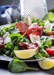Dried beef bresaola. Salad bresaola arugula baby spinach tomatoes lime and cheese parmesan.
