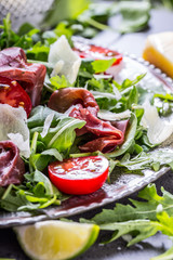 Dried beef bresaola. Salad bresaola arugula baby spinach tomatoes lime and cheese parmesan.