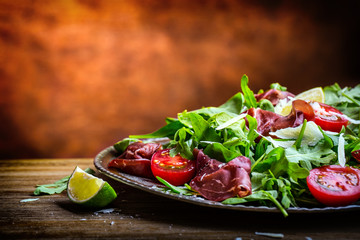 Dried beef bresaola. Salad bresaola arugula baby spinach tomatoes lime and cheese parmesan.