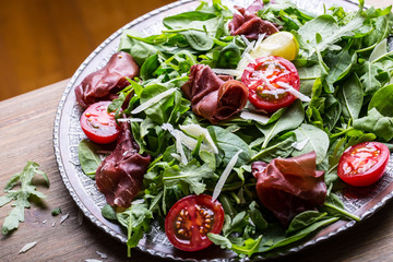 Dried beef bresaola. Salad bresaola arugula baby spinach tomatoes lime and cheese parmesan.
