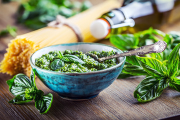 Fresh basil leaves pesto garlic and spaghetti on wooden table.