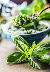 Fresh basil leaves pesto on wooden table.