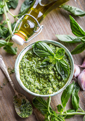 Fresh basil leaves pesto on wooden table.