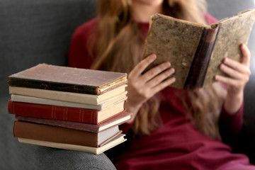 Stack of books and reading woman in armchair