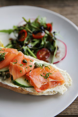smoked salmon on toasted bread with cream fresh, lemon and salad