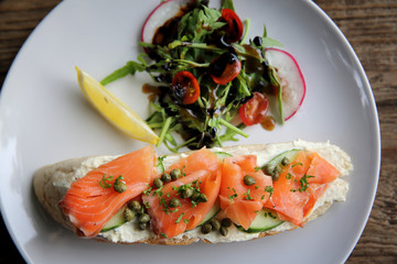 smoked salmon on toasted bread with cream fresh, lemon and salad