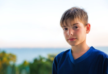 Портрет улыбающегося мальчика на фоне моря на закате