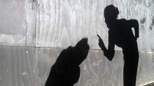 Shadow on a wall of mother child conflict: mother scolds her child (girl age 6) outdoors. Family, parenthood, childhood and children lifestyle concept